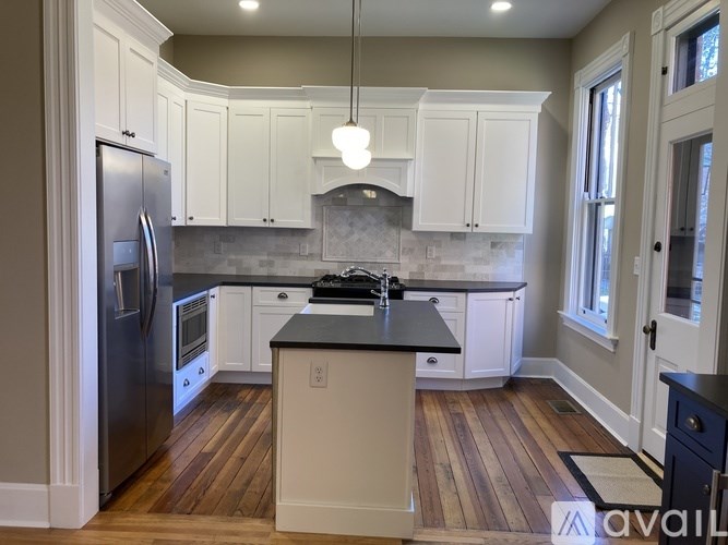 A kitchen with a refrigerator, cabinets, and a countertop.