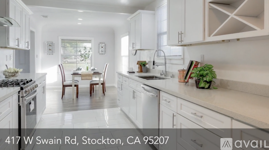 A modern kitchen with white cabinets and a dining table set for four.
