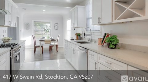 A modern kitchen with white cabinets and a dining table set for four.