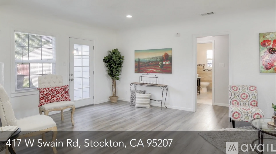 A living room with a white couch and a painting on the wall.