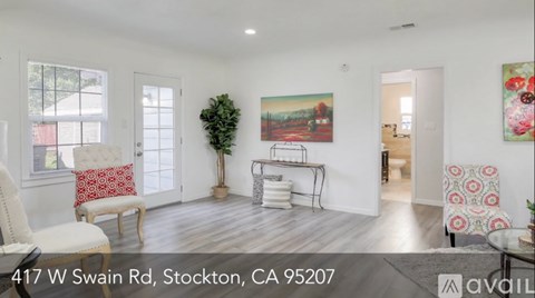 A living room with a white couch and a painting on the wall.
