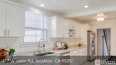 A modern kitchen with white cabinets and a stainless steel refrigerator.