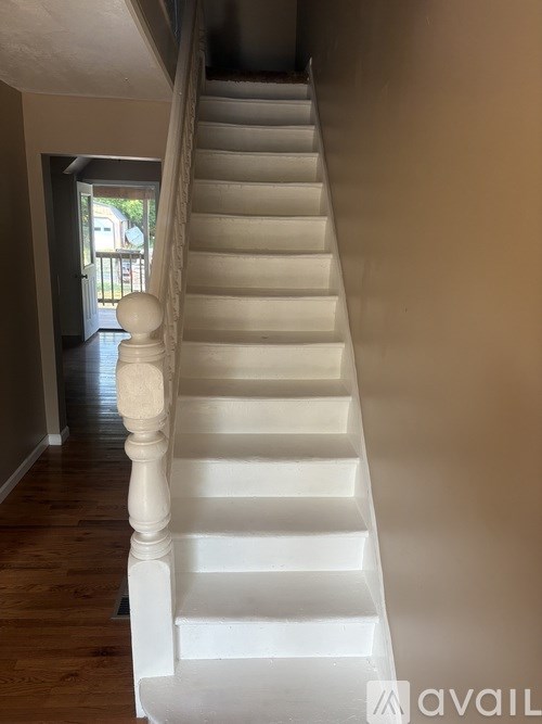 A white staircase with a wooden handrail.