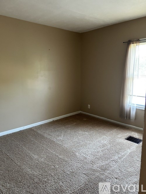 A room with beige walls and carpeted floor.