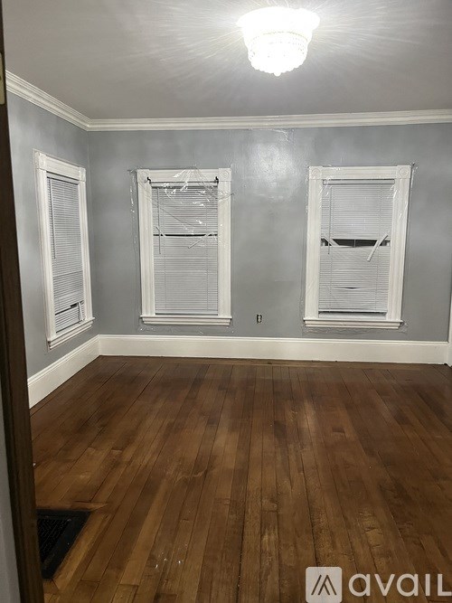 A room with wooden floors and three windows.