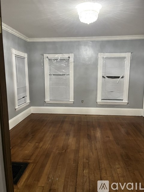 A room with wooden floors and three windows.