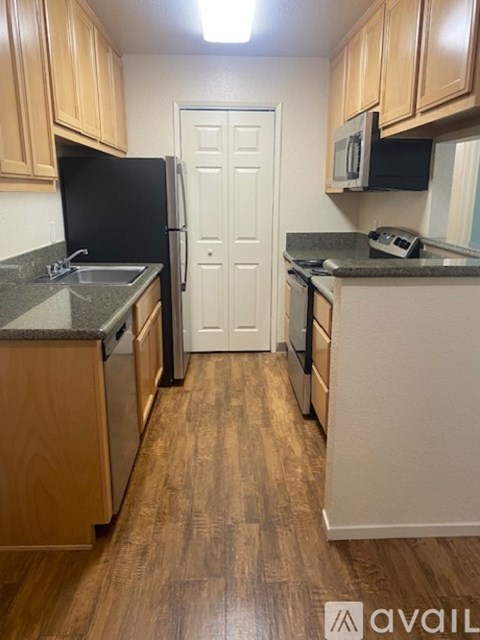 A kitchen with wooden cabinets and a black fridge.