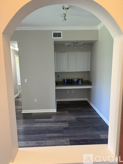 A kitchen with white cabinets and a grey floor.