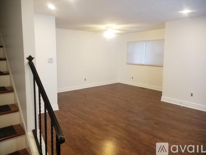 A room with wooden flooring and a staircase leading to another floor.