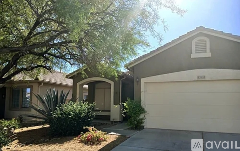 A house with a garage and a tree in front of it.