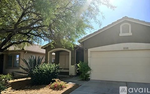 A house with a garage and a tree in front of it.