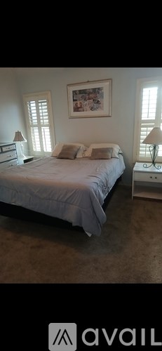 A bedroom with a bed, nightstands, and a painting on the wall.