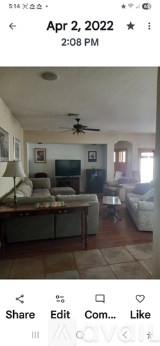 A living room with a television, couch, and a ceiling fan.