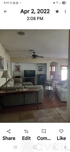 A living room with a television, couch, and a ceiling fan.
