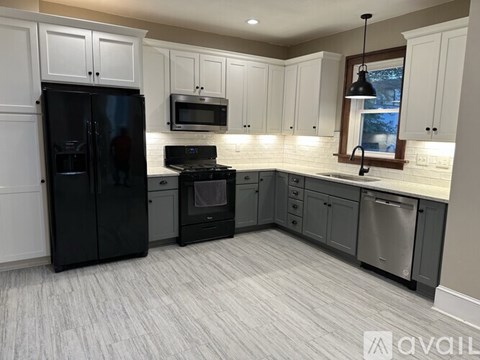 A kitchen with black appliances and white cabinets.