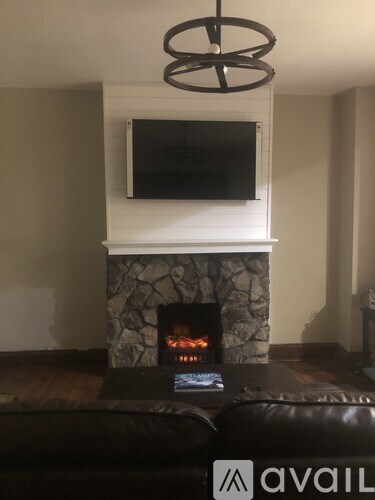 A modern living room with a stone fireplace and a flat screen TV mounted above it.