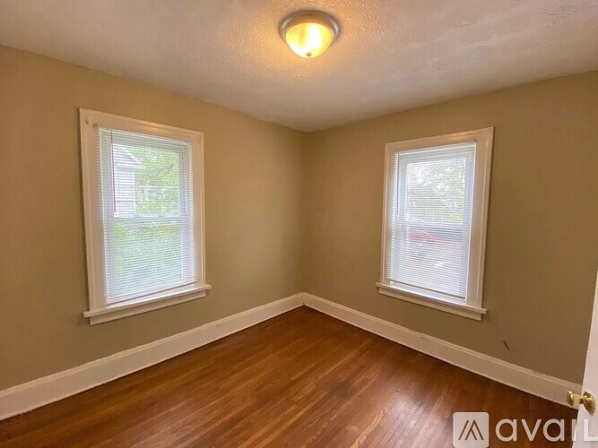 A room with two windows and wooden floors.