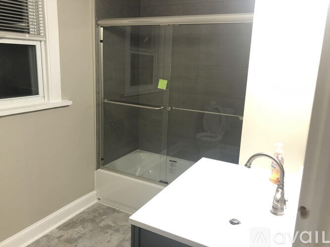 A bathroom with a glass shower door and a white sink.