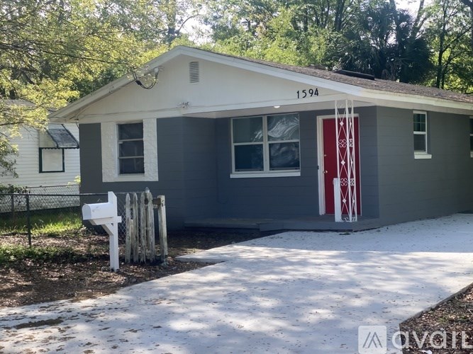 A small house with a red door and a white picket fence.