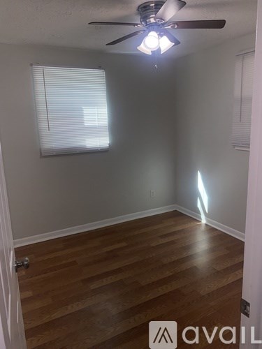 A room with a ceiling fan and wooden flooring.