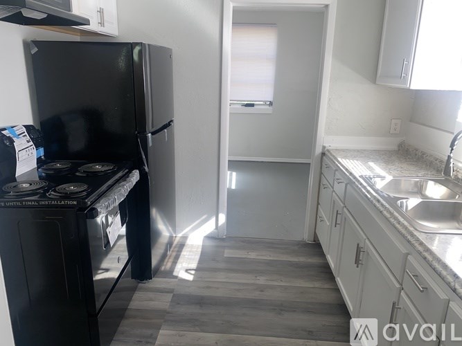 A kitchen with a black fridge and a black stove top oven.
