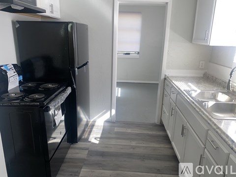 A kitchen with a black fridge and a black stove top oven.