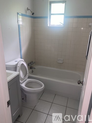 A bathroom with a toilet, tub, and window.