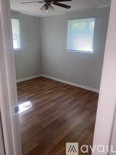 A room with wooden flooring and a ceiling fan.