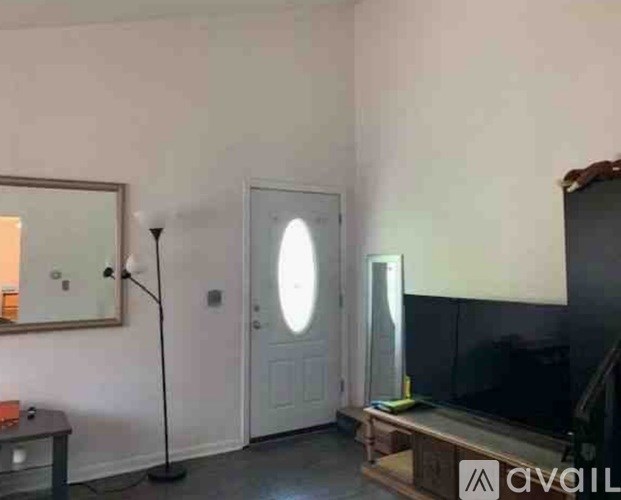 A room with a white door, a mirror, a floor lamp, and a wooden bench.