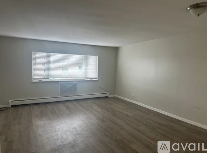 A room with a window and wooden flooring is available for rent.