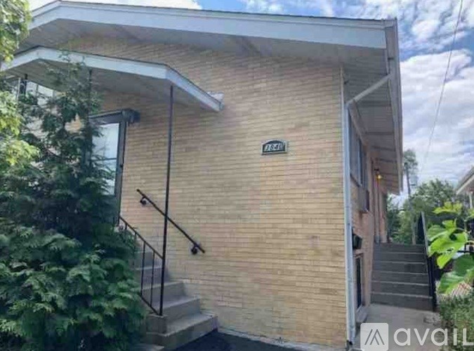 A house with a brick exterior and a staircase leading to the door.
