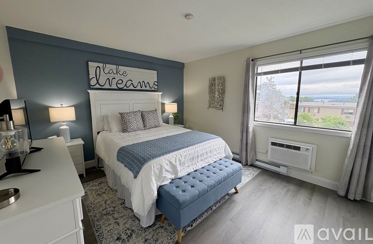 A bedroom with a bed, nightstand, and window overlooking a body of water.
