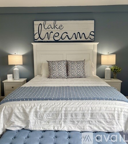 A bed with a white headboard and a sign above it that says "lake dreams".