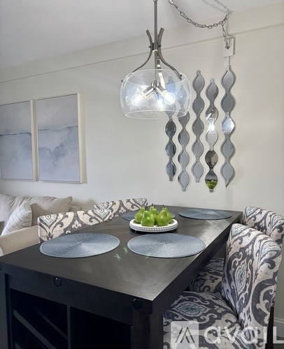 A modern dining room with a glass chandelier and a black dining table.