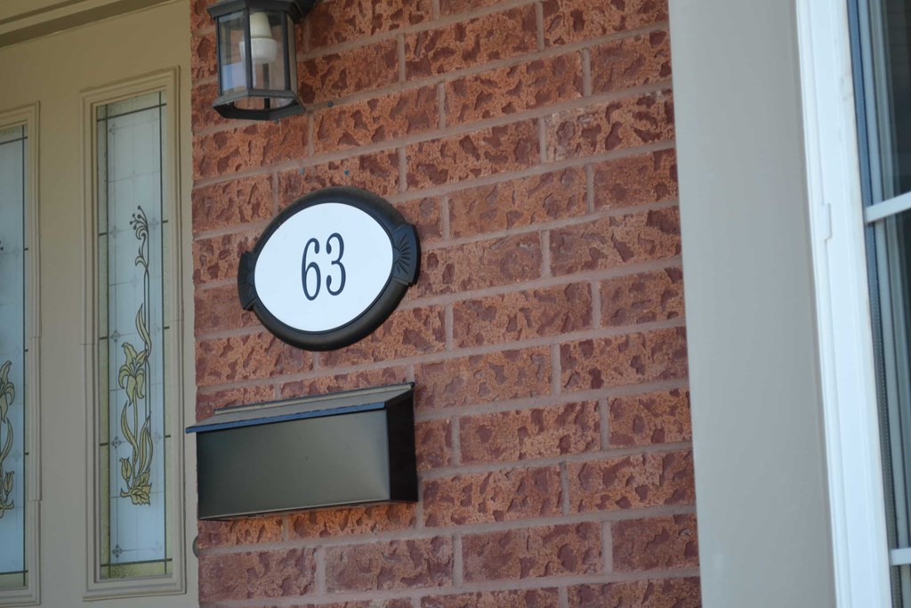 A house number 63 is displayed on a brick wall.
