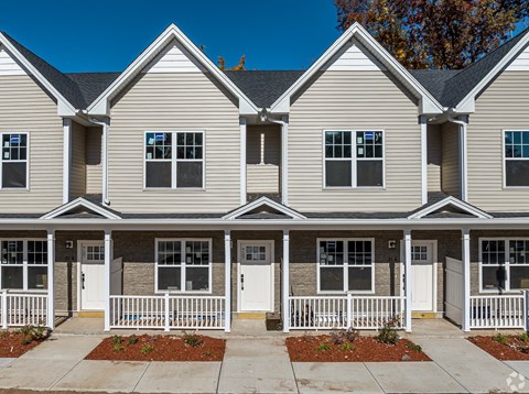 A row of houses with white fences and front yards.