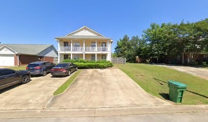 A house with a carport and a green trash can.