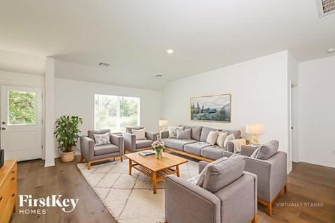 A living room with a grey couch and a painting on the wall.