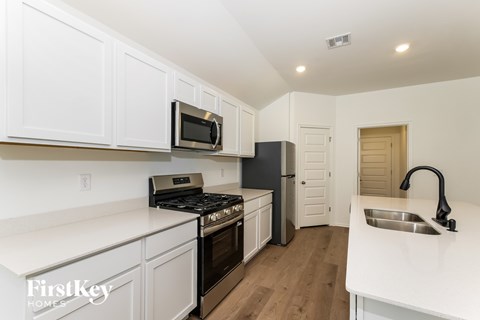 A kitchen with white cabinets and a black fridge.