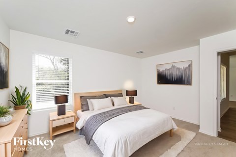 A bedroom with a bed, nightstand, and a painting on the wall.