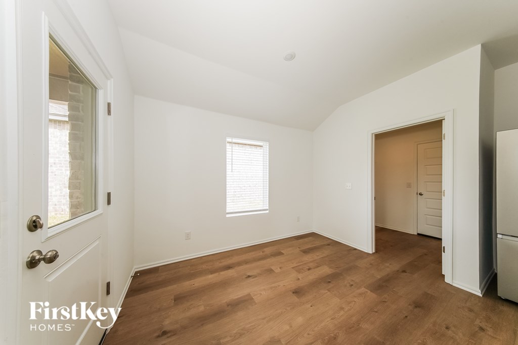 A room with wooden floors and a refrigerator in the corner.