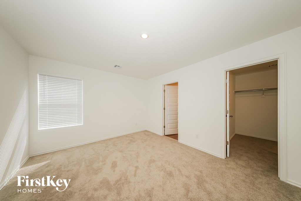 A room with a carpeted floor and a window with blinds.