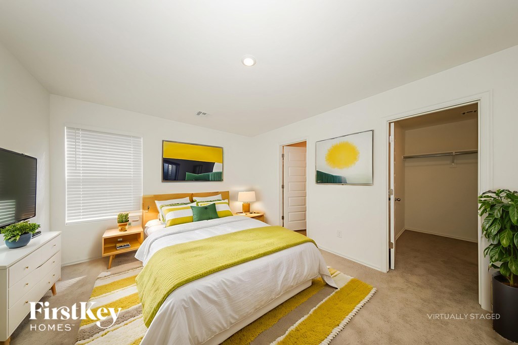 A bedroom with a bed, nightstand, and a painting on the wall.