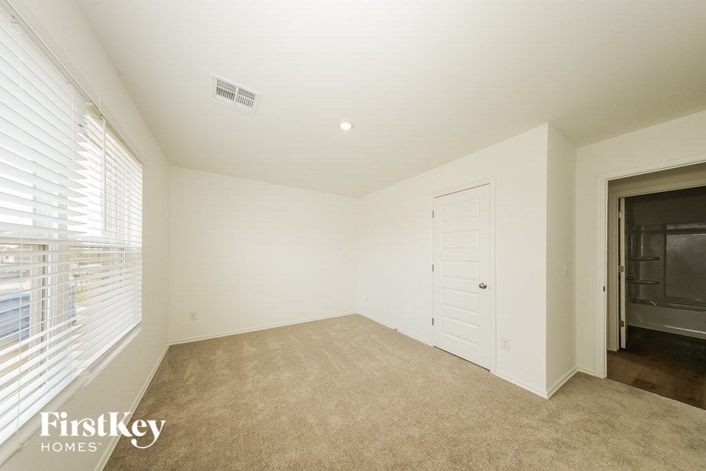 A room with a carpeted floor and a door leading to a kitchen.