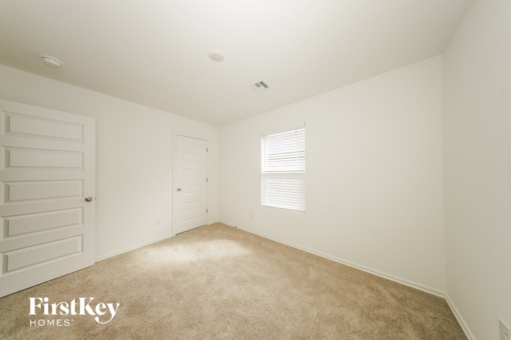 A room with a carpeted floor and a window with blinds.