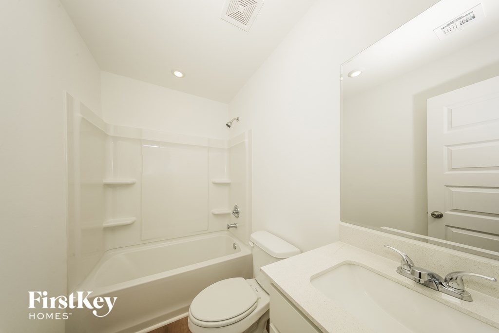 A white bathroom with a tub, toilet, and sink.