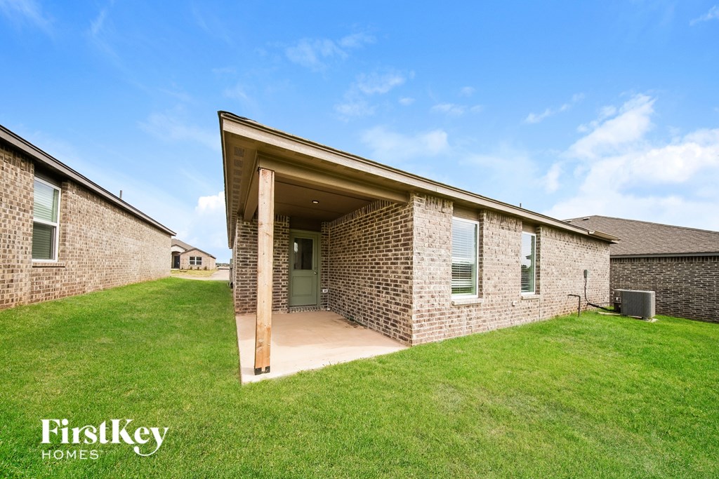 A brick house with a large front yard and a clear blue sky.