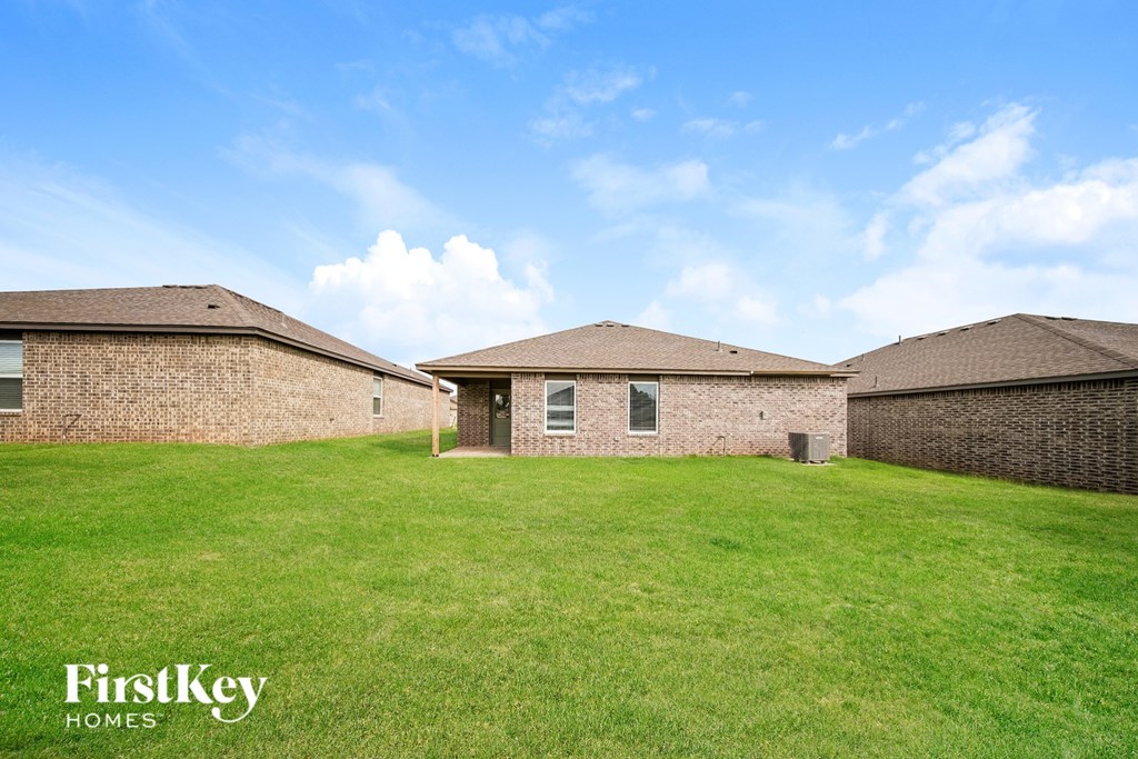 A grassy field with three houses and a blue sky.
