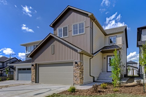 A modern house with a garage door and a stone wall.