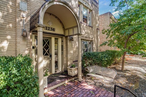 A building with the number 1236 on it has a doorway with a bench outside.